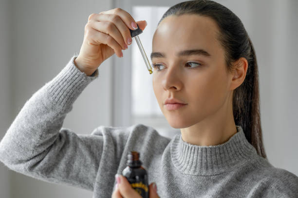 A woman applying face serum with a dropper as part of a skincare routine.